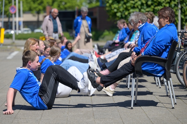 Sporters en ouderen doen samen een oefening bij de sociale sportschool
